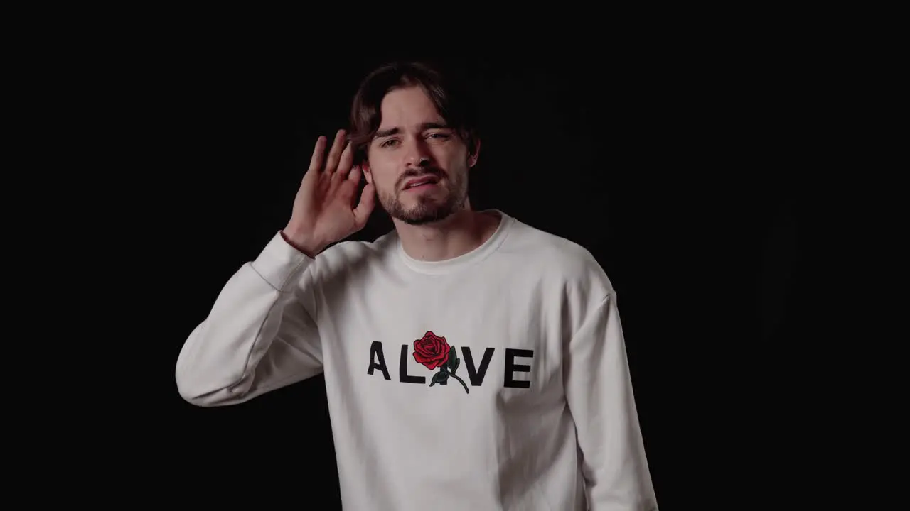 Trendy Young Man listening with hand deaf gesture wide black background