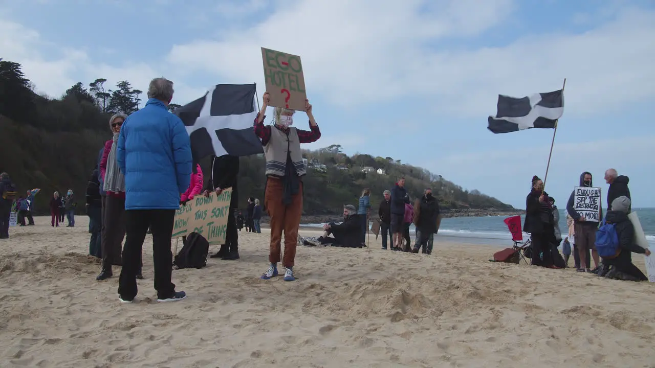 Flags fly as protesters begin to gather on beach in front of Carbis Bay Hotel St Ives Cornwall