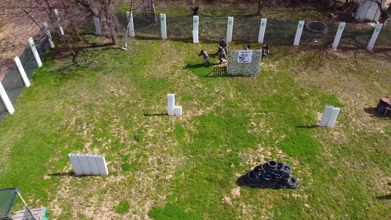 Paintball players running from their base at the start of the match drone shot