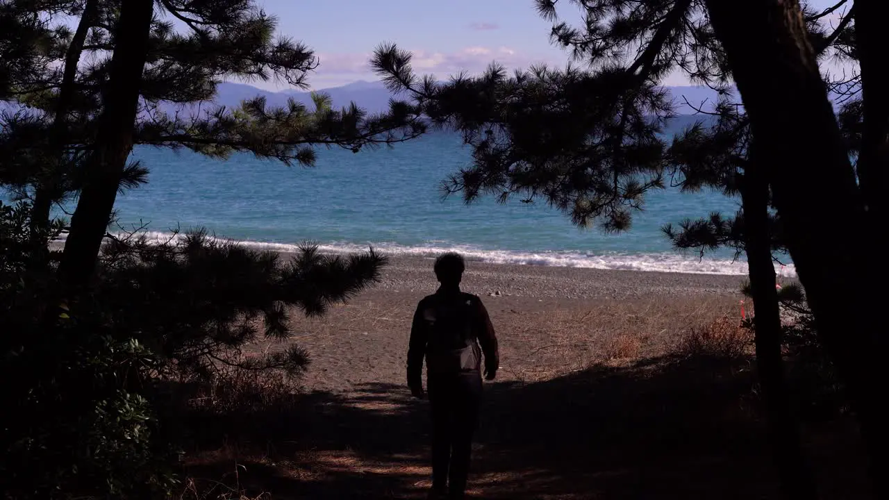 Silhouette of male walking towards opening on beach during daytime