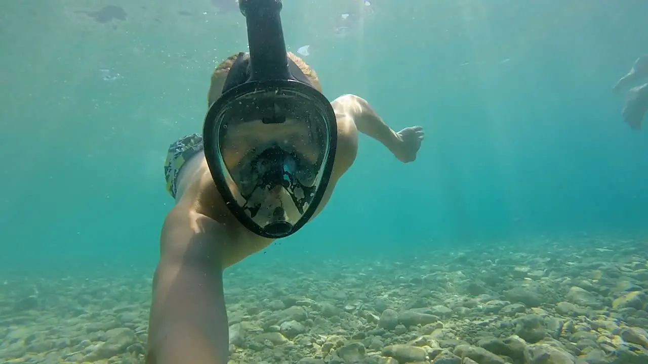 The boy swims underwater in a diving mask