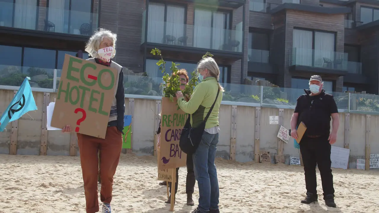 Women demonstrating on the beach in front of the Carbis Bay Hotel in St Ives Cornwall whilst man looks on