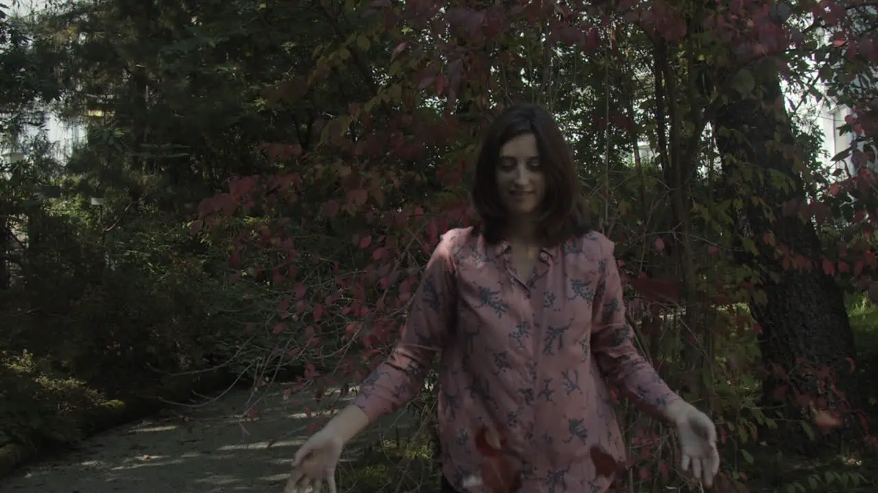 Young woman tossing up leaves in autumnn slow motion wide shot