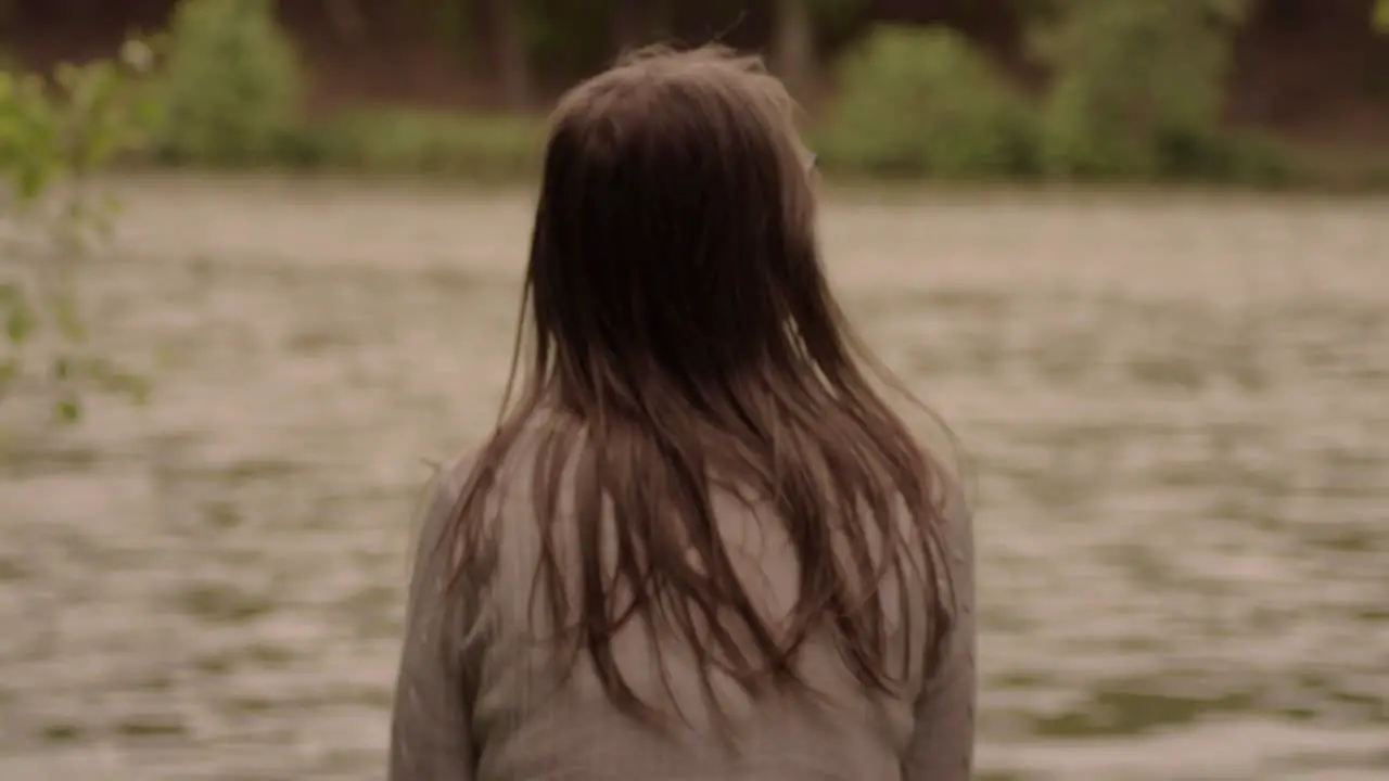 Woman in solitude relaxes looking out onto flowing river