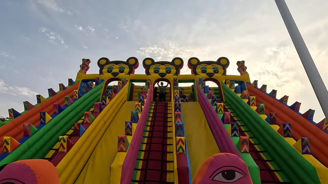 In a cinematic scene little kids are having fun sliding down the Mickey Mouse Sliding Rides