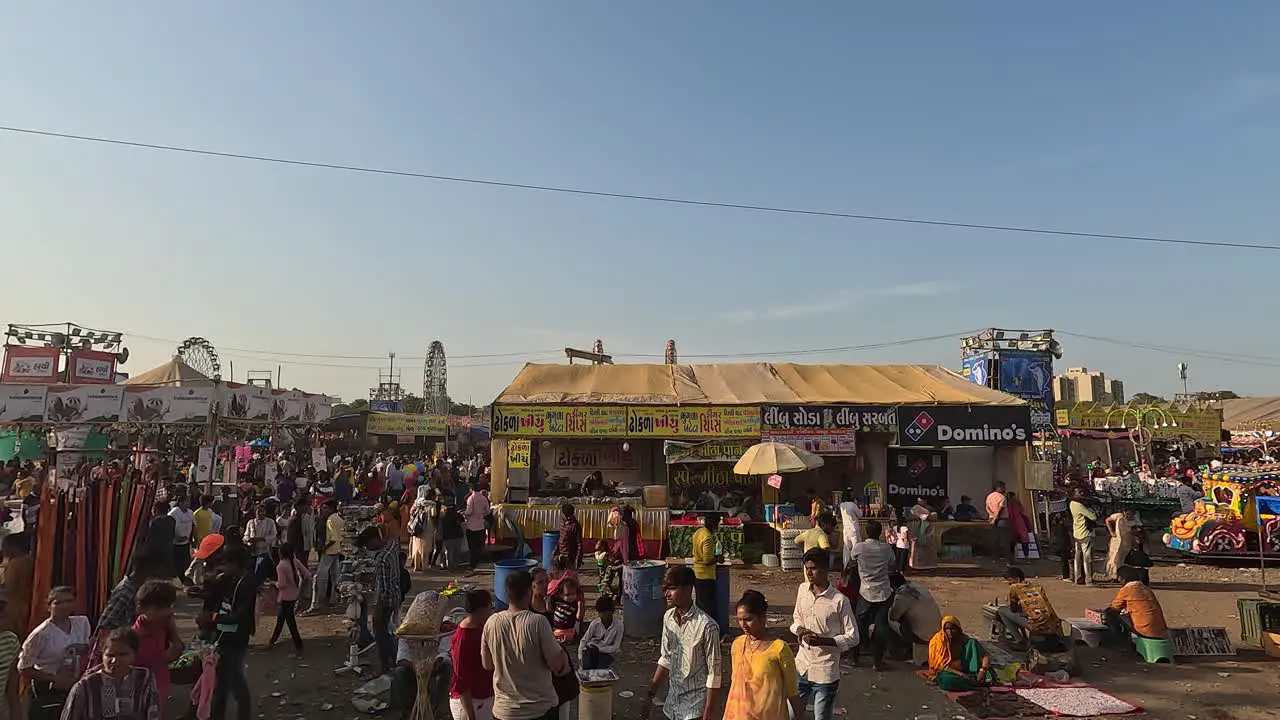 During the day people are roaming around the amusement park and enjoying the food stalls and drink stalls