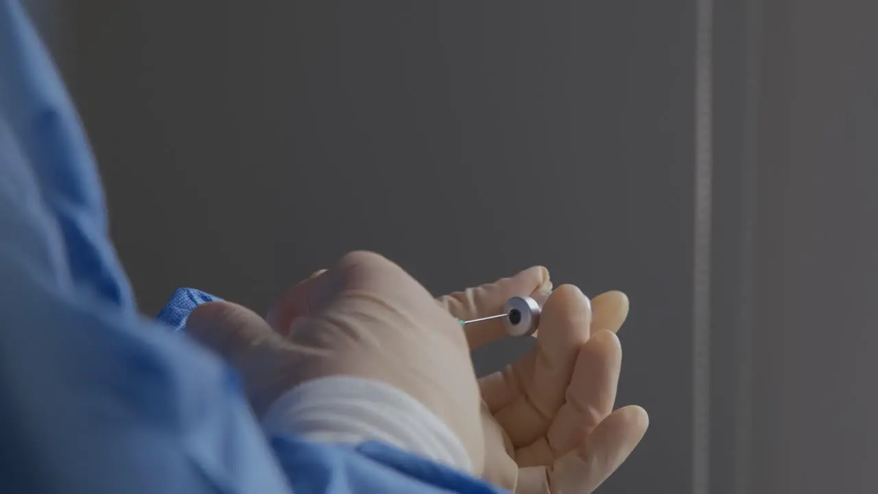 Side view of a healthcare worker inserting a syringe into a vial of the new COVID-19 vaccine