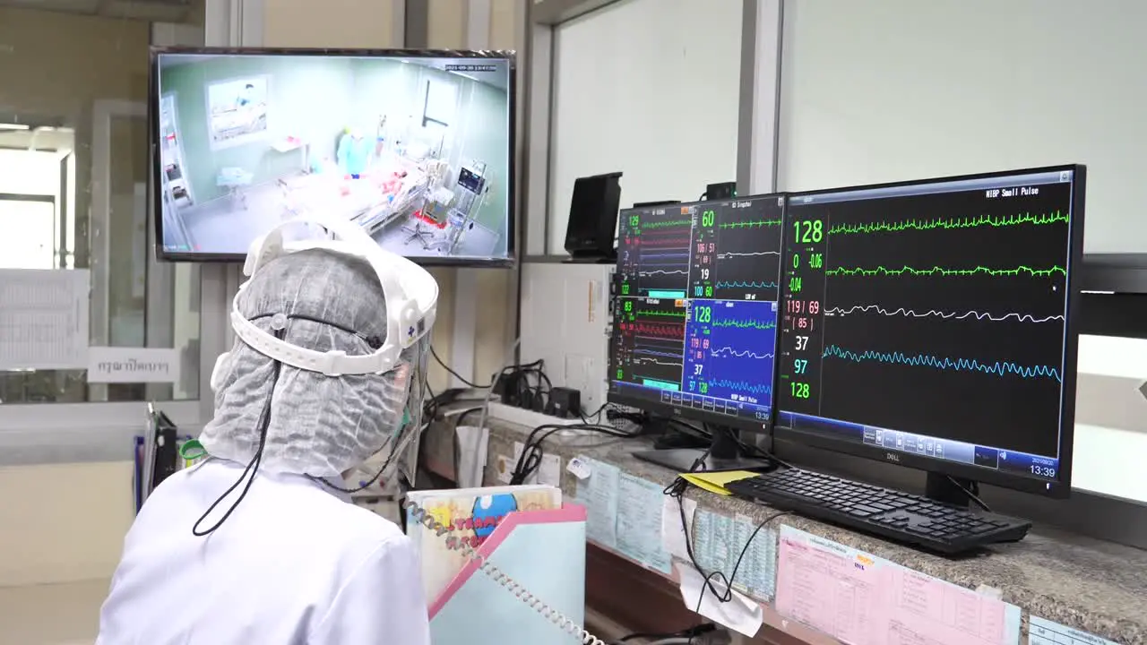 Doctor Monitoring The COVID-19 Infected Patient Via Screen From Isolation Unit