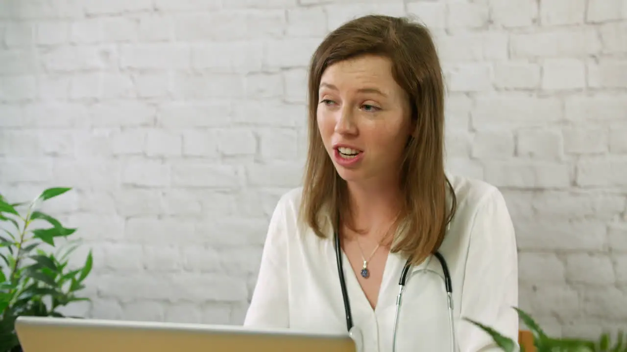 A young female GP junior doctor talking to a patient in a doctors office