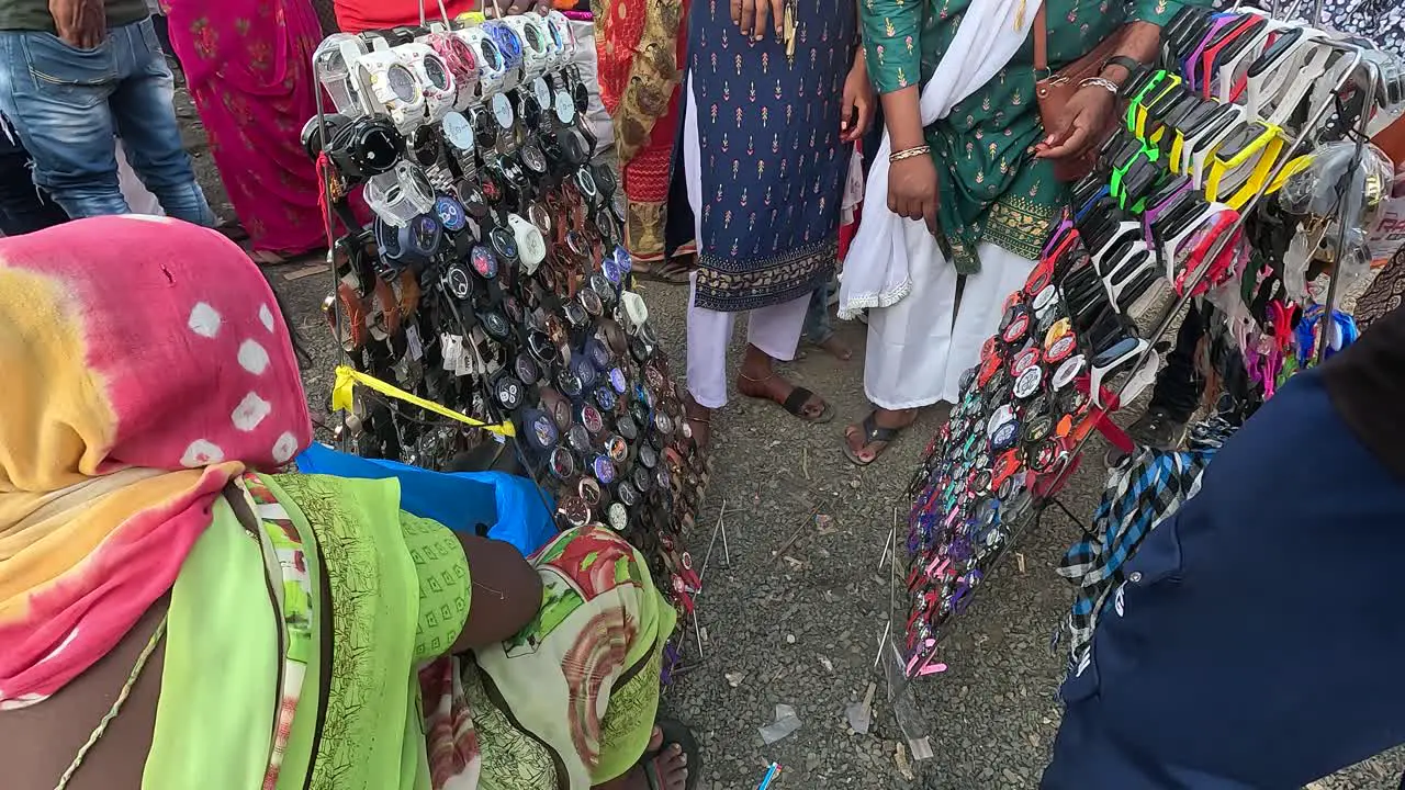 A woman shopkeeper is selling hand clocks at a fair