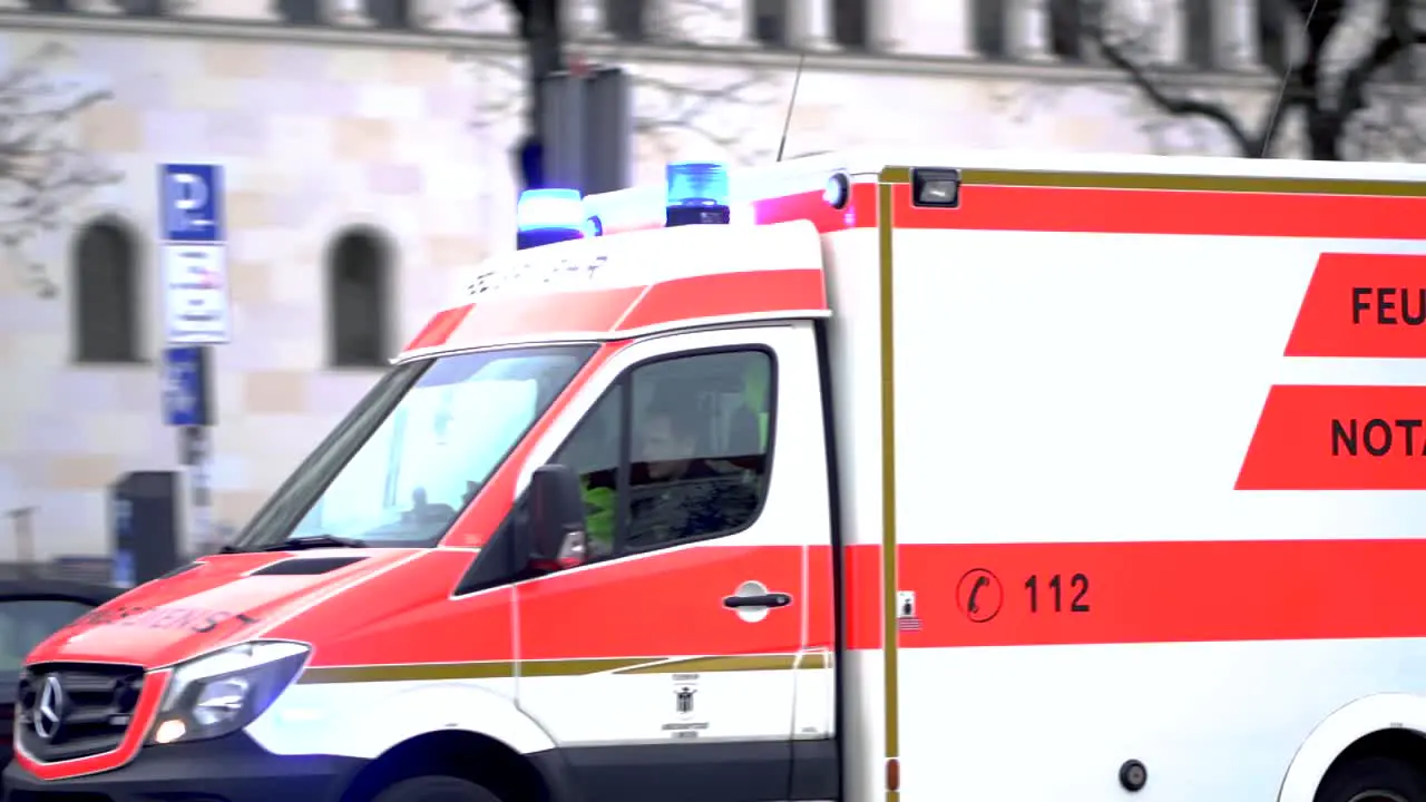 Slow motion of german ambulance driving down the road with sirens