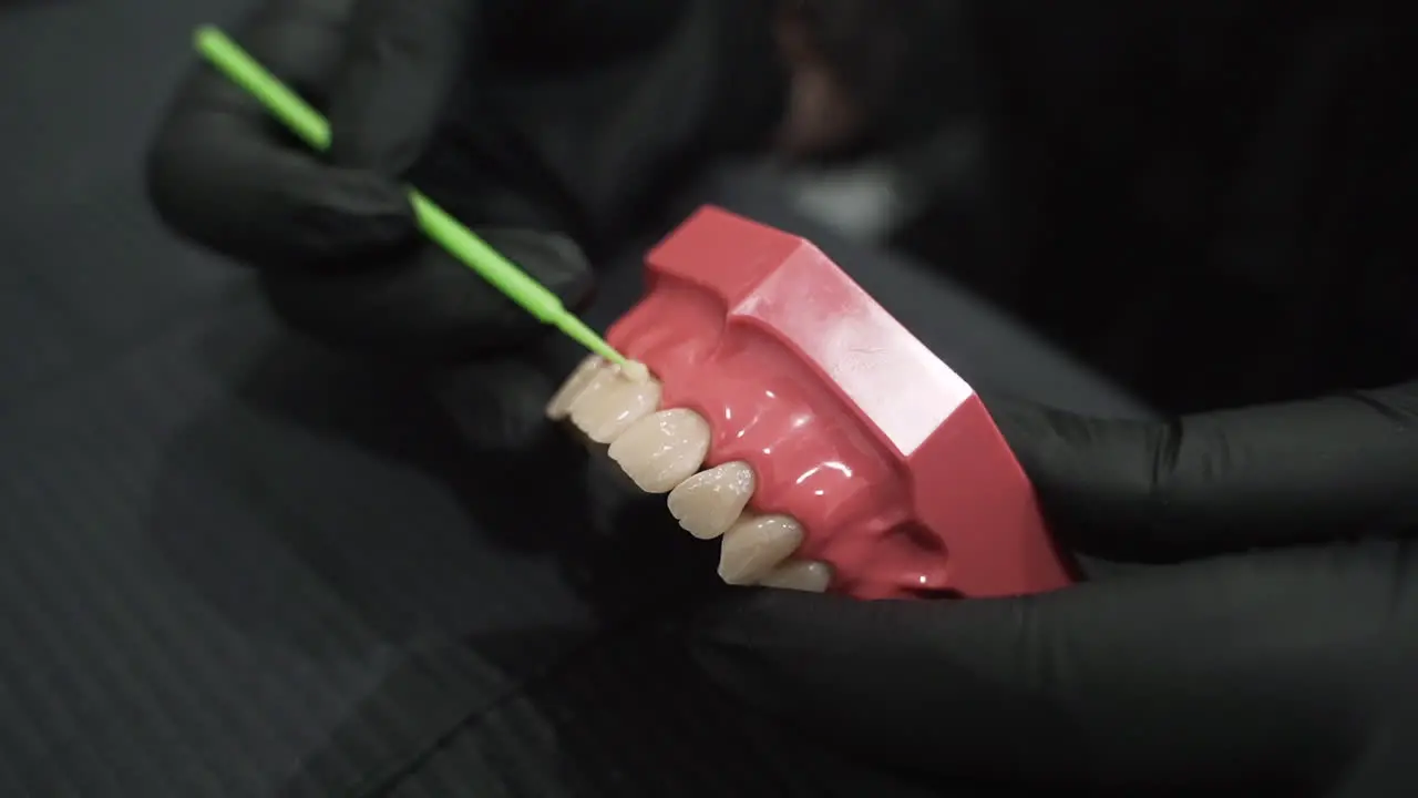 Layering composite resin adhesive on denture for demonstration Close up