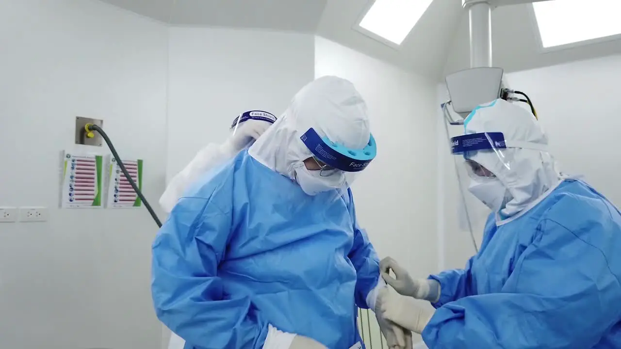 Asian Nurse and Assistant Help Doctor Put On PPE Isolation Gown Personal Protection Equipment