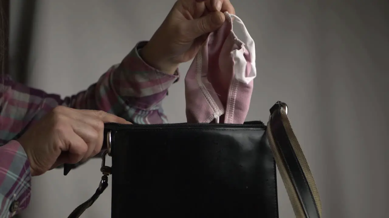 Woman getting face mask out of handbag medium shot