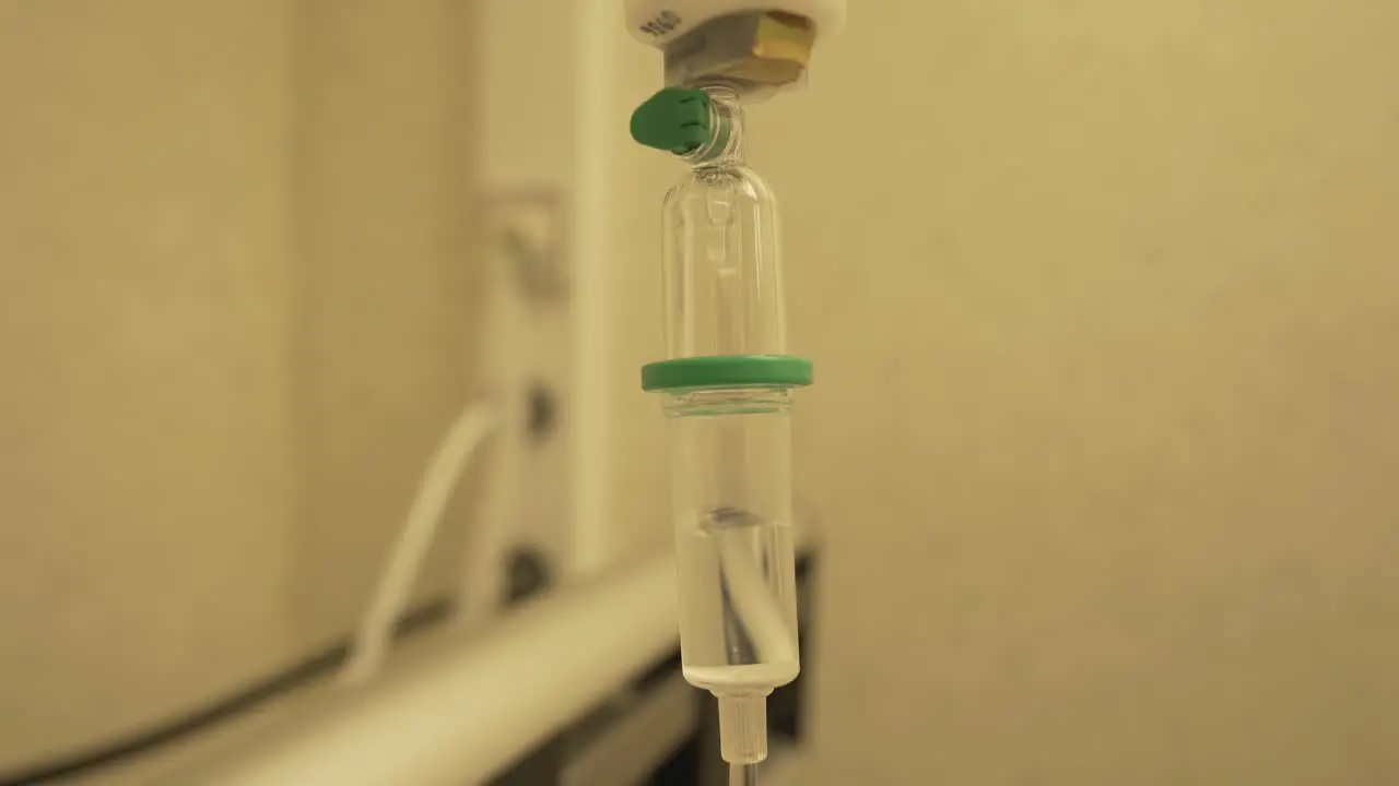 Close view of medical plastic giving set transparent reservoir filled it intravenous fluid and slow drops for treatment of patient in hospital during coronavirus pandemia