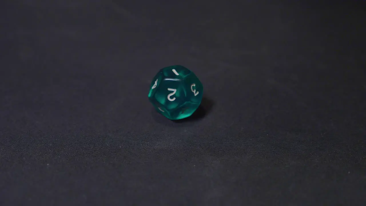 Twelve face green dice rolling on the black surface slow motion