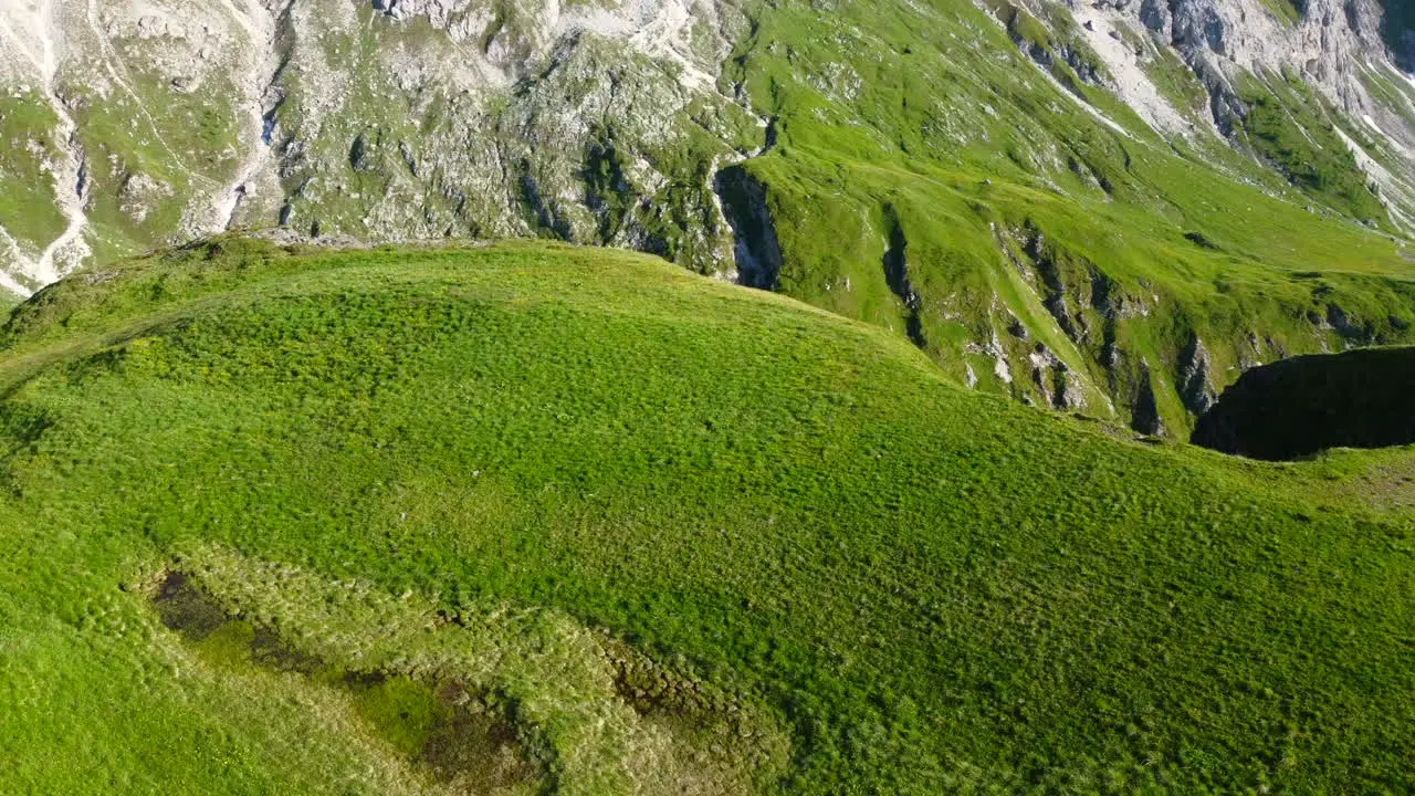 aerial landscape slow motion of lush green grassy meadow in the Dolomites mountain range on a summer day