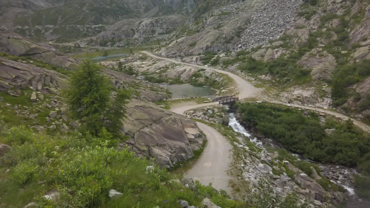 Scenic landscape of the road and a small lake in the middle of the green and rocky mountains