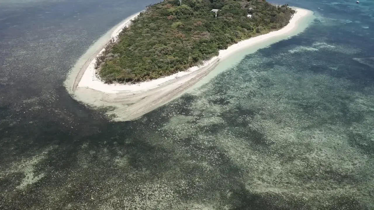 Drone aerial of green tropical island by a clear blue water reef