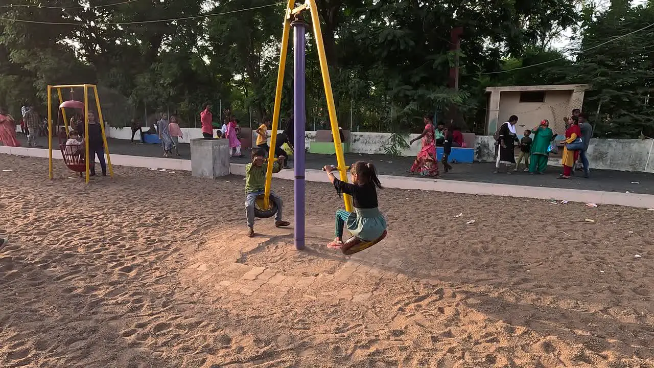 Two small children are enjoying the merry-go-round ride and a lot of traffic has gathered in the park