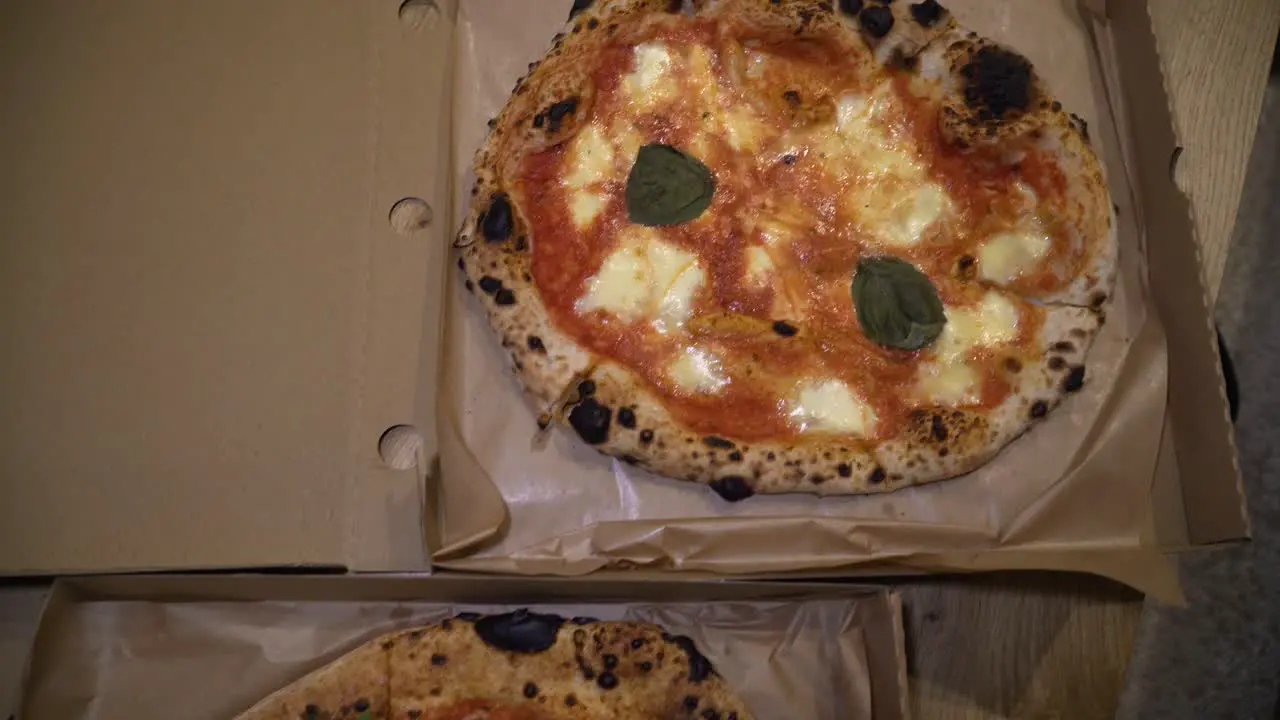 sliding top down shot of delicious Italian pizzas delivered in boxes on the table