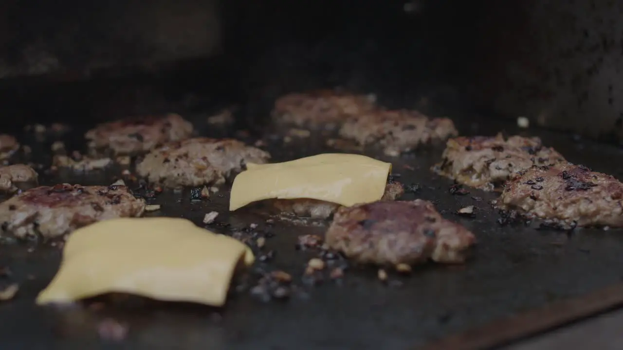 Adding cheese slice on top of frying beef meat on a grill