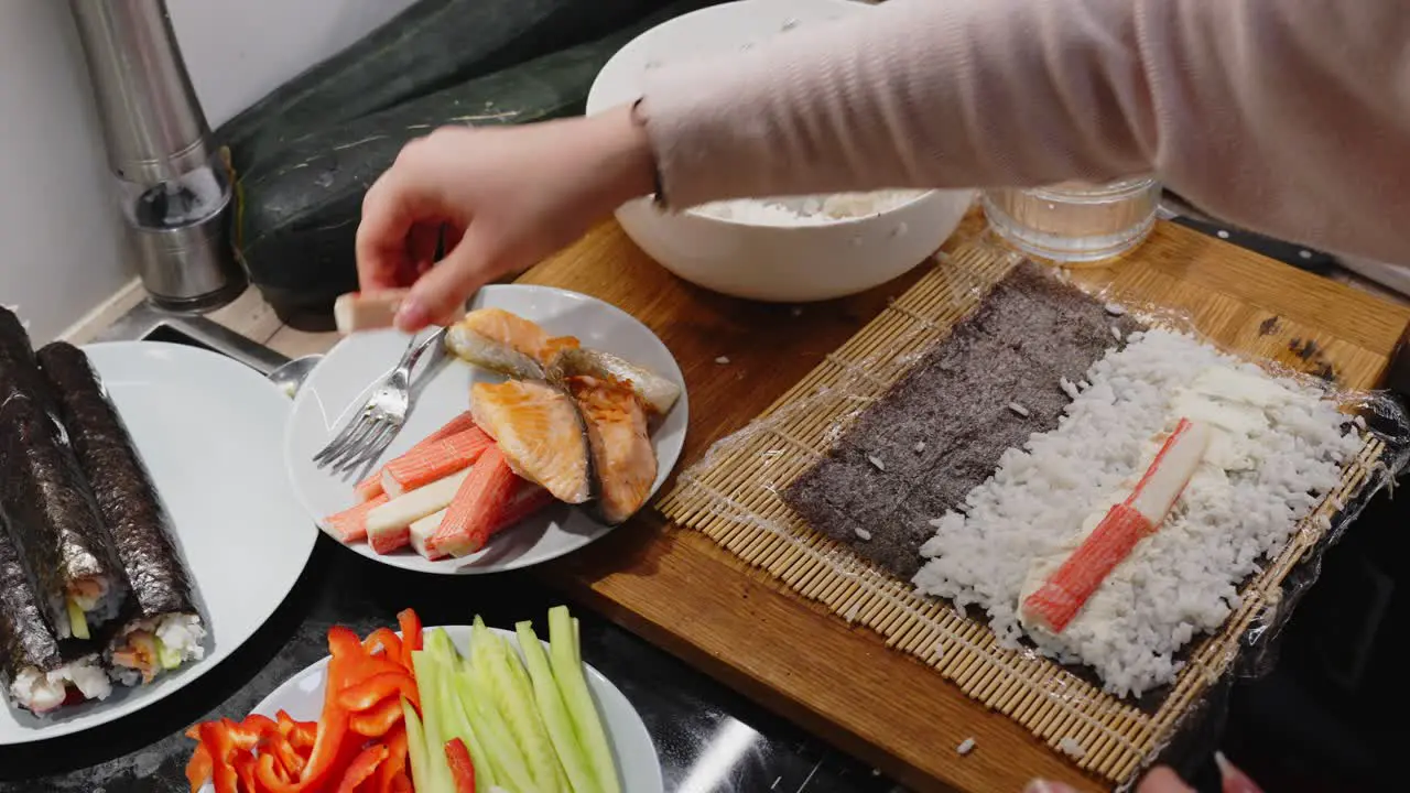 Person Adding Crab On Sushi Roll Preparing For Dinner At Home