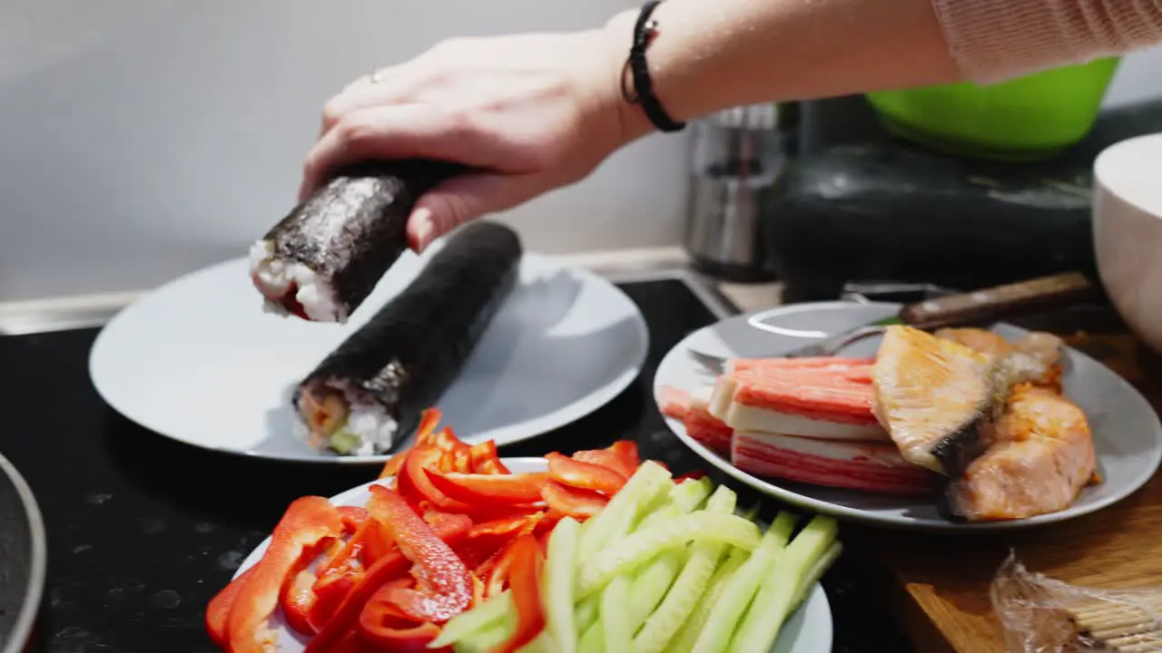 Person Holding Green Sushi Roll To Place It In White Plate Homemade Preparation