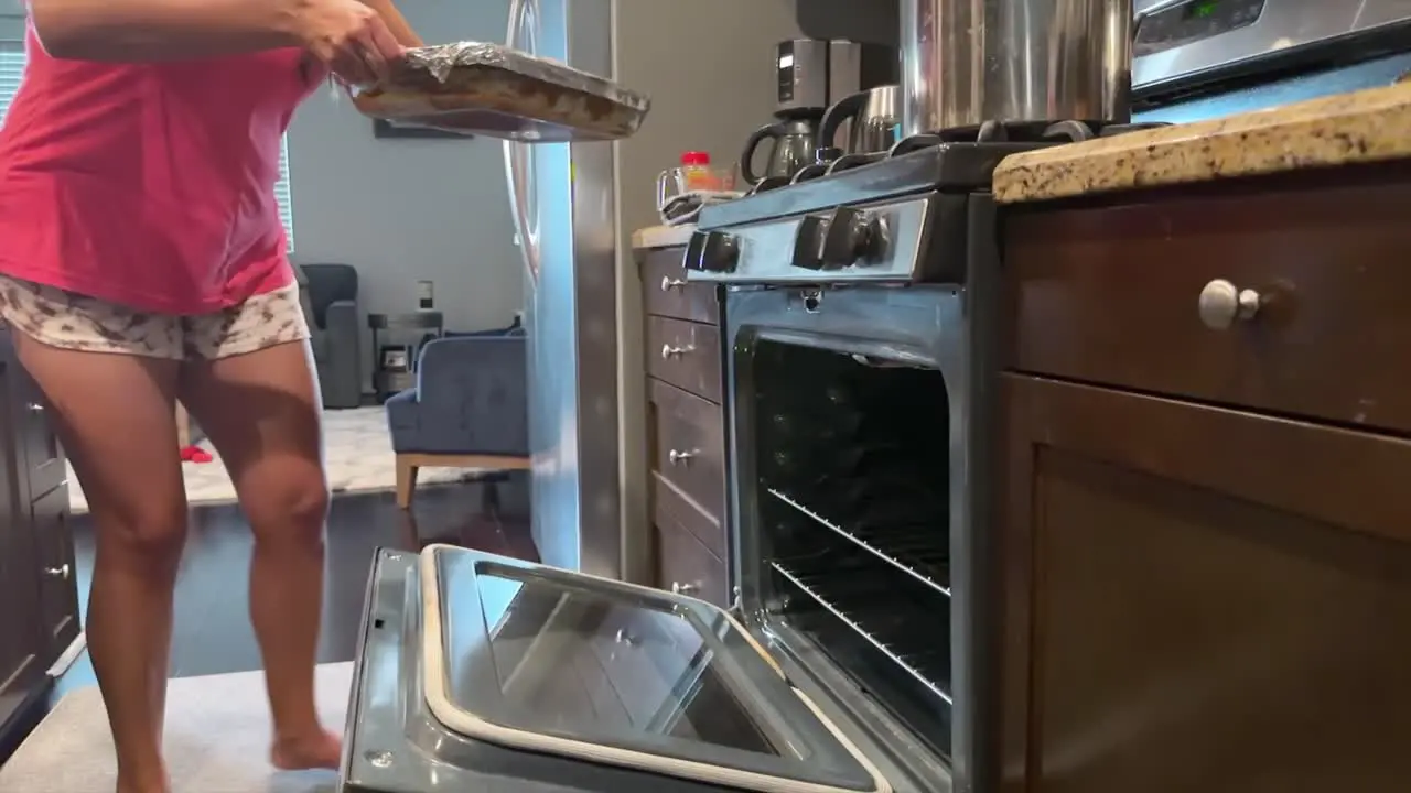 Hispanic Woman putting lasagna pirex into Oven in Slow motion Homemade meal