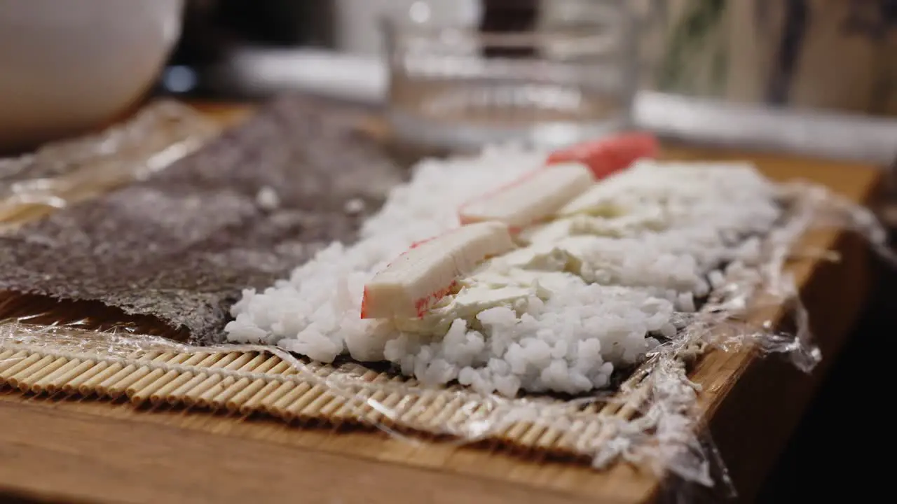 Close Up Of Person Adding Crab On Sushi Roll Preparing For Dinner At Home