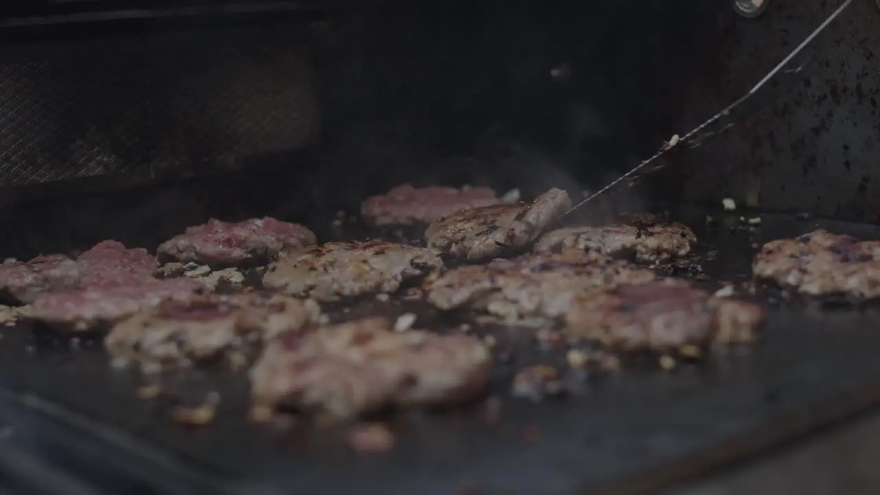 Frying ground beef meat on a grill together with diced onion