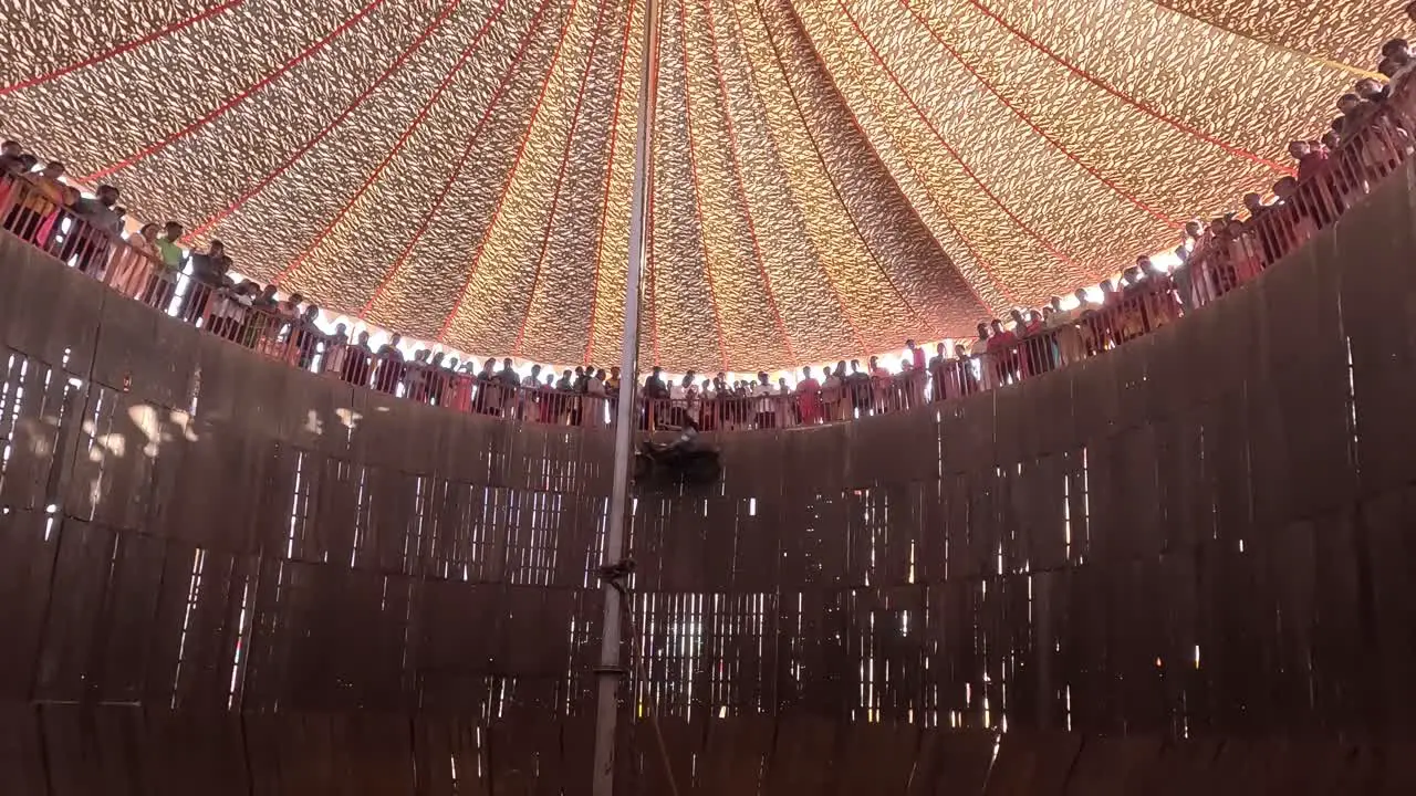 The well of death scene in which thousands of people watch the bikes and cars in the well of death the cars and bikes passing by the camera