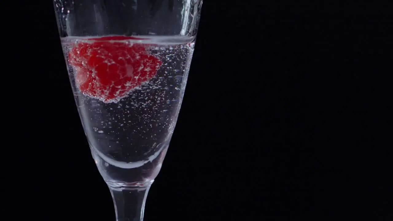 Frozen Raspberry drifting inside glass of clear water