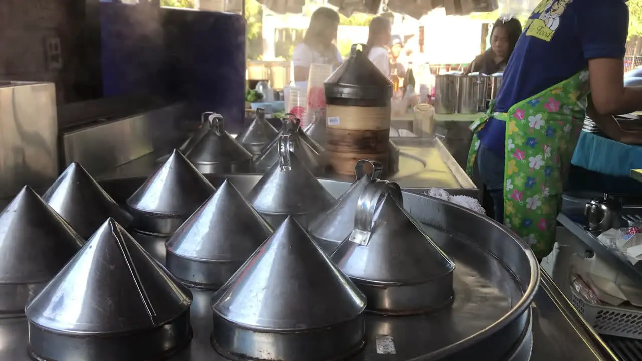 hand held shot of freshly steaming dim sum tin steel pots in a food stall and roadside restaurant in Rawai Phuket Thailand