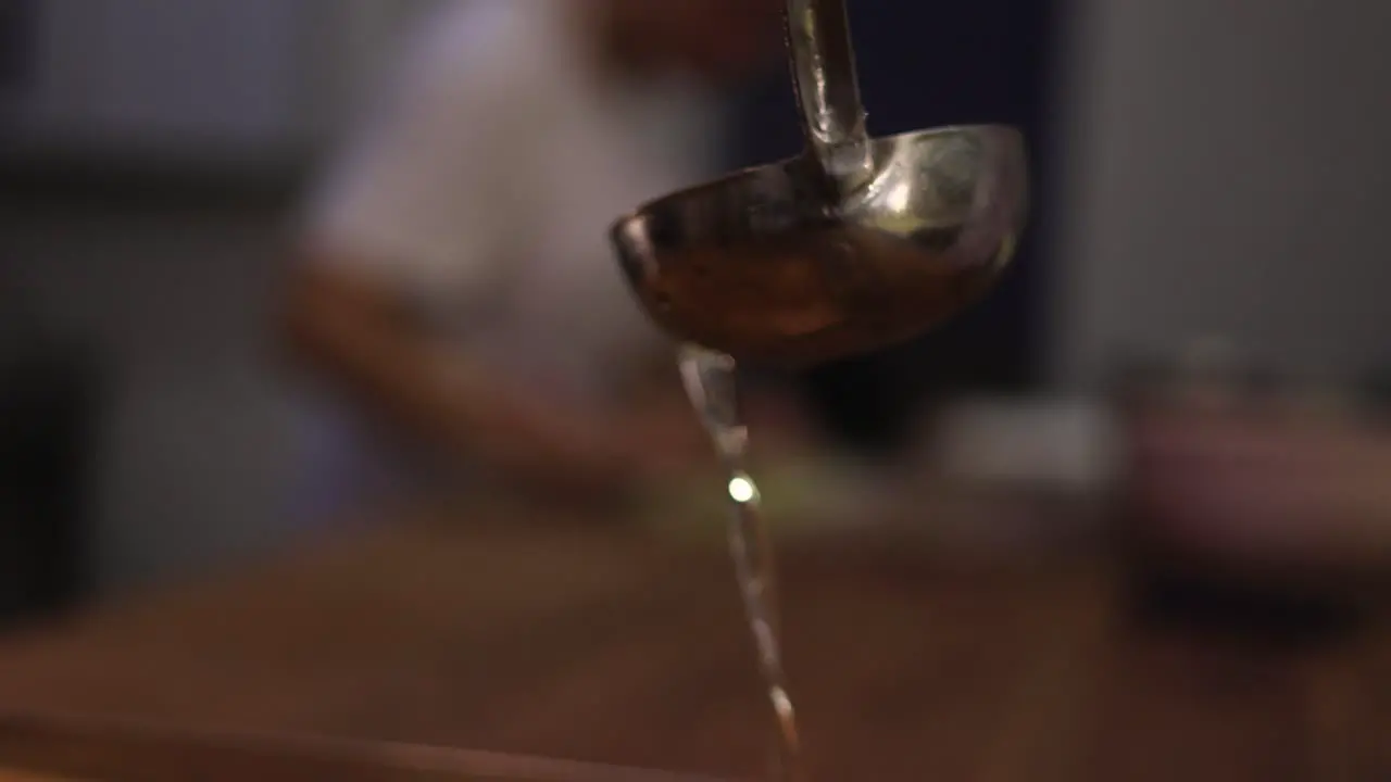 Cooking spoon pouring syrup over the dessert with the pastry chef in background