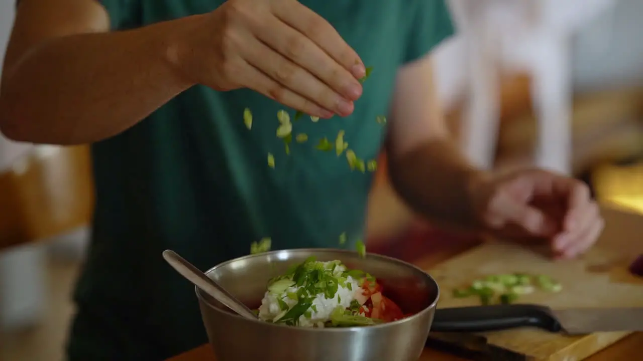 man adds chopped green onion to a salad filmed in slow motion