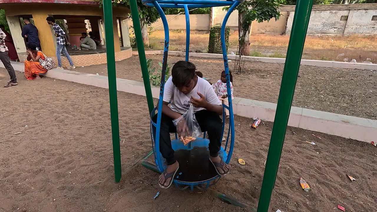 A little boy is eating wafers while sitting on a ride in an amusement park on a holiday