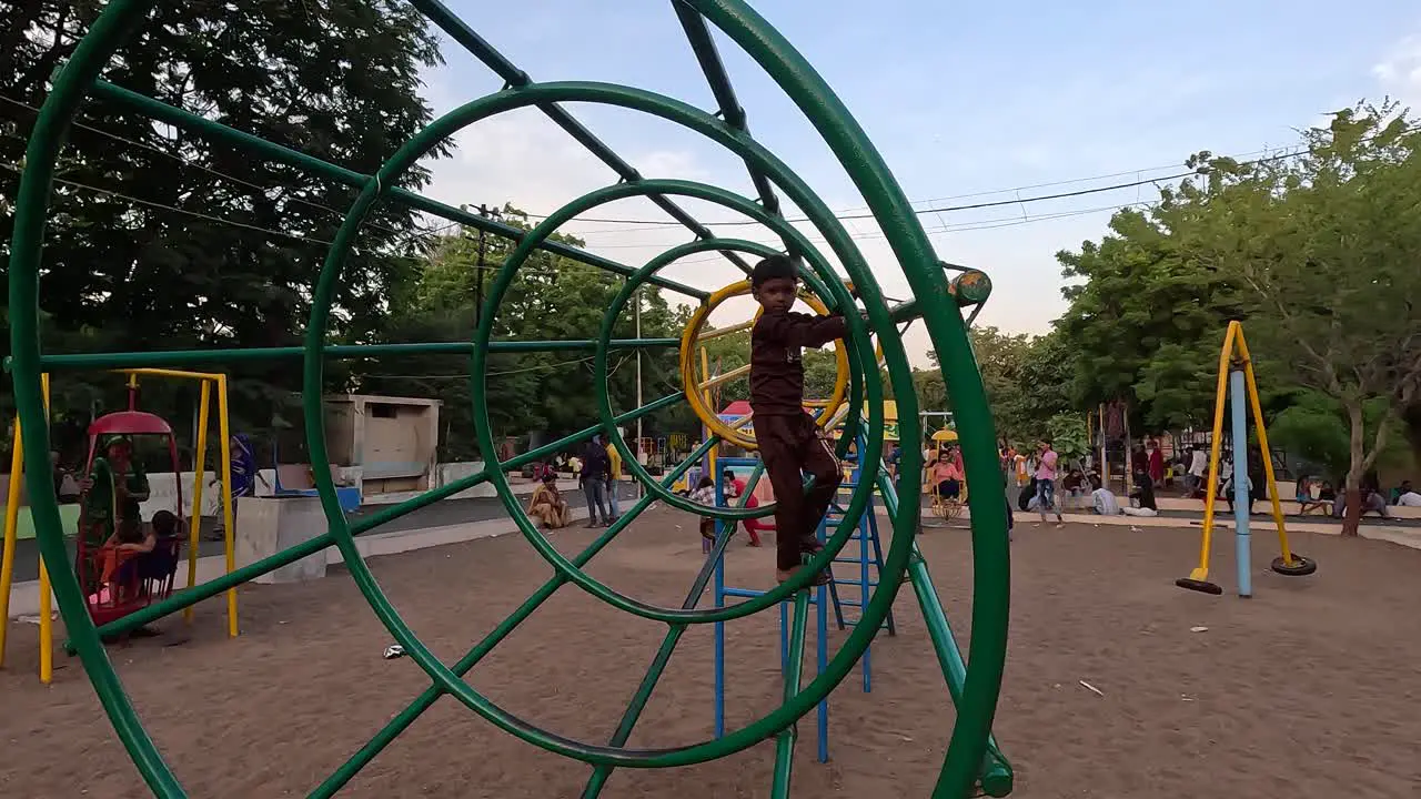 Little child playing on exercise equipment in public park during