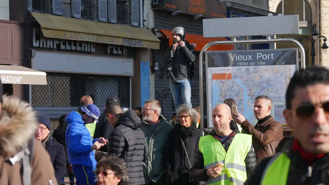 A photojournalist puts his helmet on while observing a crowd of yellow jacket demonstrators next to a subway station in Marseille south of France