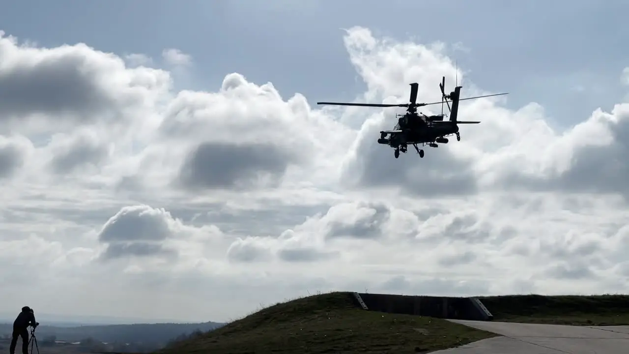 Slow Motion Ah-64 Apache Helicopter Hovers In Place Over Grassy Field At The Grafenwoehr Training Area Germany