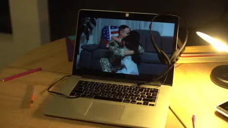 military man with daughter hugging video on laptop