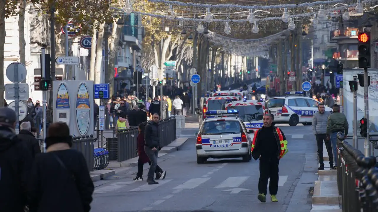 A union worker during a yellow jacket demonstration in Marseille walks on the street next to a red light and six police vehicles turning at an angle