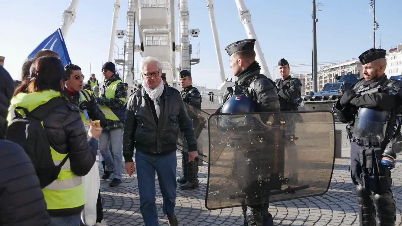 Yellow jacket demonstrator with a french flag talks to police in full riot gear