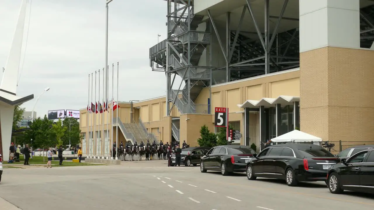 Canadian military funeral ceremony outside sports stadium black limousines parked