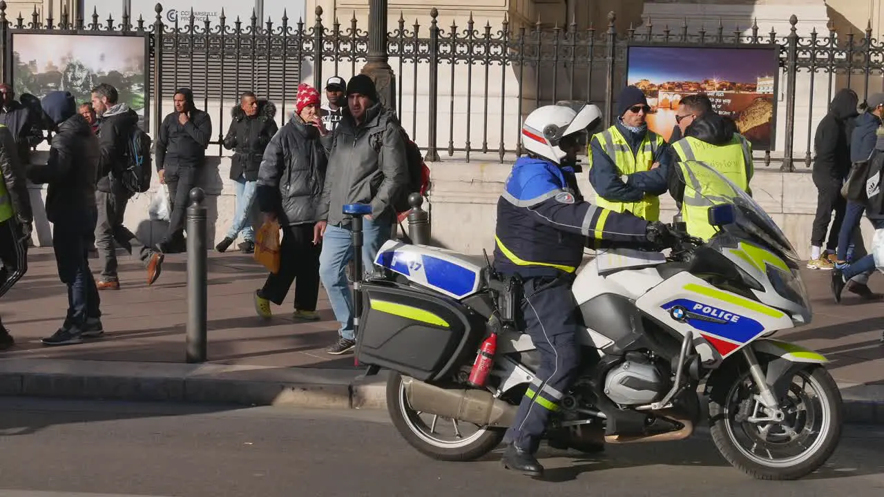 A police officer with a helmet turns on his motorbike and lives the scene while yellow jacket protesters awaiting for the demonstration to begin talk peacefully in Marseille south of France