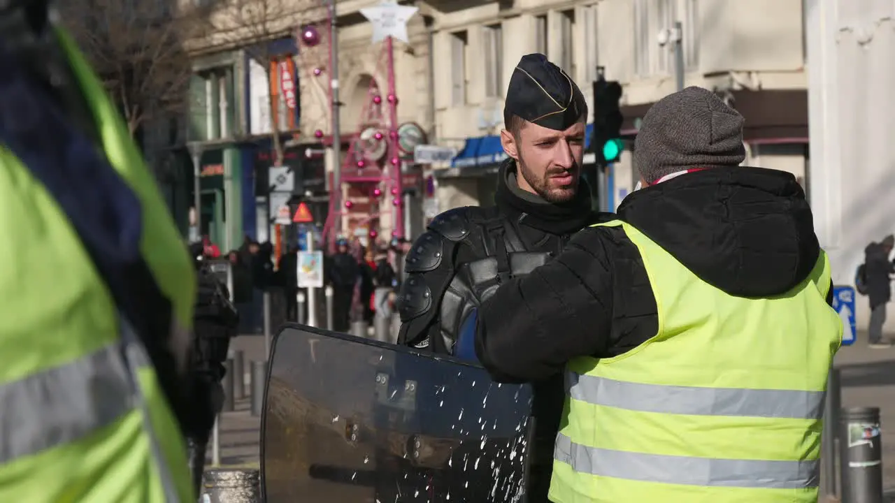 A yellow jacket demonstrator moves towards a police officer in full riot gear to ask a question