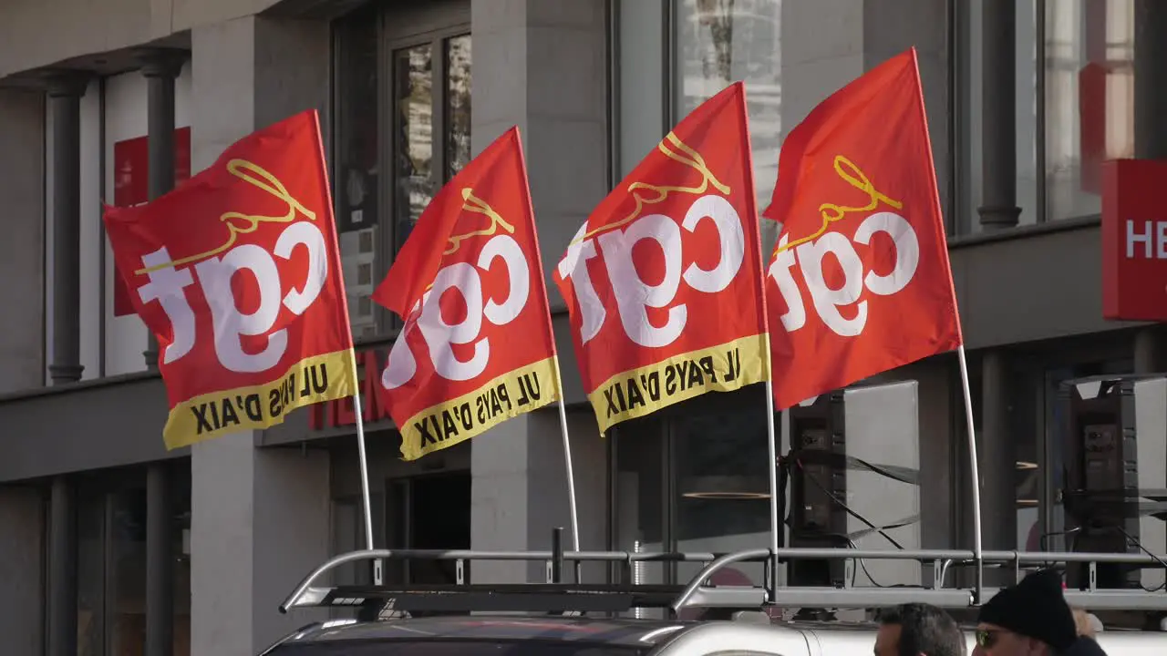 Four red union flags from CGT moving in the wind on a top of a demonstration vehicle