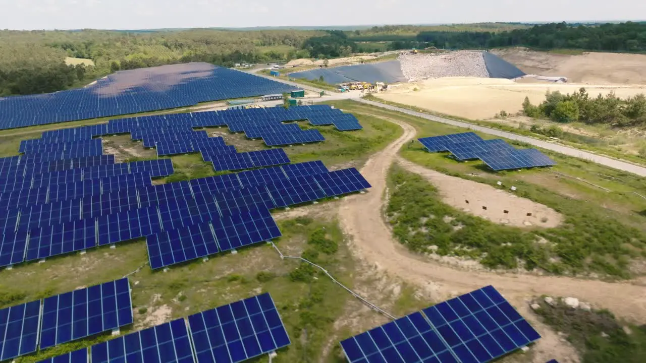 Lateral and forward motion in solar panels seen from a drone with a landfill in the background