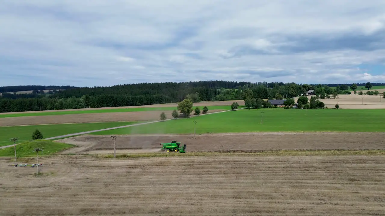 A view of efficient combined harvesting in action when the camera from the drone captures the side of the combine in motion and zooms out at the same time