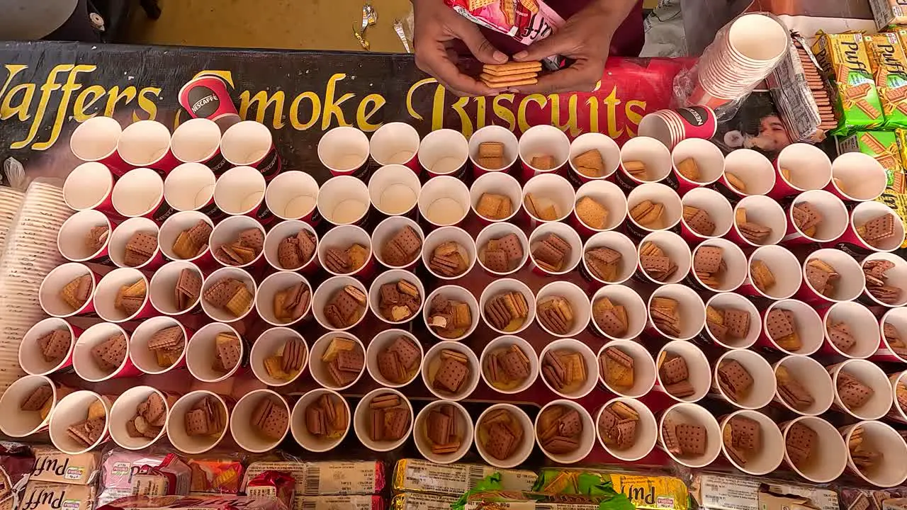 Top angle sot shopkeeper filling a cup with biscuits wafers smoke biscuits shopkeeper making delicious and tasty biscuits